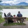 Eine arabische Familie sitzt auf einer Bank am Ufer des Eibsees bei Garmisch-Partenkirchen und genießt das Bergpanorama.