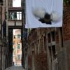 Es gibt sie auch einzeln in Venedig: fliegende Taube vor Bettlaken-Leinwand in einer Gasse im Viertel Cannaregio. 