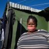Mandisa Makubalo, 41, vor ihrer Blechhütte am Rande von Kapstadt. Sie erkrankte an Covid-19 – aber das war nicht ihr einziges Problem.  	