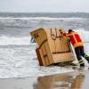 Ein Feuerwehrmann versucht, in Kiel-Schiksee einen Strandkorb vor den Flutwellen der Ostsee zu sichern.