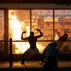 Ein Mann posiert während der gewaltsamen Proteste in Minneapolis vor einem Feuer einem Geschäft.