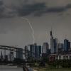Hessen, Frankfurt am Main: Ein Blitz durchzuckt den Abendhimmel während eines Gewitters über den Frankfurter Bankentürmen.