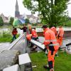 Mitarbeiter des Neu-Ulmer Baubetriebshofs bringen Schutzwände an der Donau an.