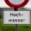 Ein Hinweisschilder mit der Aufschrift «Hochwasser» steht an einem vom Regen überfluteten Radweg.