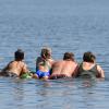 Eine Familie schwimmt auf einer Luftmatratze im Wasser eines Sees.