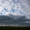 Windräder werden bei wolkigem Himmel kurzzeitig von der tiefstehenden Sonne beleuchtet.