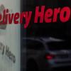 Das Logo und der Schriftzug des Essenslieferdienstes Delivery Hero spiegelt sich in einer Scheibe.