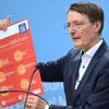 Bundesgesundheitsminister Karl Lauterbach (SPD) hält ein Plakat zum Thema Hitzeschutz hoch.