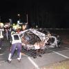 Rettungskräfte stehen am Wrack eines zerstörten Autos nach einem Unfall an einem Bahnübergang.