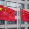 Flaggen der Volksrepublik China wehen an Fahnenmasten eines Hotels.