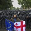 Die Proteste gegen das "russische Gesetz" und die Regierung in Tiflis gehen trotz großer Präsenz der Sicherheitskräfte weiter: Eine Frau mit einer georgischen National- und einer EU-Fahne steht vor Polizisten, die eine Straße blockieren. 