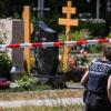 Eine Polizistin geht über den abgesperrten Teil an einem Tatort auf einem Friedhof.