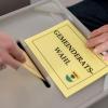 Ein Mann gibt im Wahllokal seinen Stimmzettel zur Gemeinderatswahl ab.