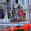 Feuerwehrmänner stehen vor dem Mehrfamilienhaus in Solingen, in dem es gebrannt hat.