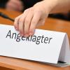 Ein Schild mit der Aufschrift "Angeklagter" wird auf die Gerichtsbank gestellt.