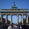 Viele Touristen kommen bei Sonnenschein und blauem Himmel zum Brandenburger Tor, um Erinnerungsfotos zu machen.