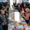 Besucherinnen und Besucher der Leipziger Buchmesse schauen sich einen Bücherstand an.