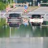 Zwei Autos stehen unter einer Saarbrücke im Stadtteil Schönbach im Hochwasser.