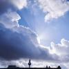 Sonnenstrahlen kommen hinter einer dunklen Wolke über dem Fernsehturm hervor.