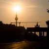 Das Brandenburger Tor und der Fernsehturm sind im Gegenlicht der aufgehenden Sonne zu sehen.