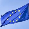 Eine Europaflagge weht vor blauem Himmel. Die Flagge der EU ist blau mit goldenen Sternen darauf.