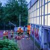 Rettungskräfte stehen vor einer Turnhalle. Vier Kinder sind durch das Dach einer Sporthalle gefallen.