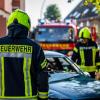 Feuerwehrleute stehen um ein Auto, das einen Unfall gehabt hat.