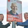 Thomas Mix (l), ehrenamtlicher Bürgermeister von Podelzig (Märkisch-Oderland) und Thomas Mix (SPD), ehrenamtlicher Bürgermeister von Buckow (Märkisch-Oderland) stehen an einem Wahlplakat.