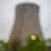Der Kühlturm des stillgelegte Kernkraftwerks Isar 2 hinter einer Fensterscheibe mit Regentropfen.