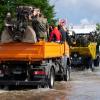 Soldaten fahren mit einem Lastwagen über eine überflutete Straße im Ortskern.