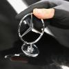 Eine Mitarbeiterin arbeitet an einer Motorhaube an einem Mercedes-Emblem.