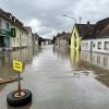 In Günzburg müssen Menschen aus Häusern gerettet werden, bevor weitere Wassermassen kommen. Der Verkehr wird von Polizei und Einsatzkräften geregelt.