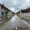 In Günzburg müssen Menschen aus Häusern gerettet werden, bevor weitere Wassermassen kommen. Der Verkehr wird von Polizei und Einsatzkräften geregelt.