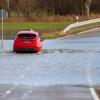 Ein Auto fährt auf einer mit Hochwasser überfluteten Straße zwischen Daugendorf und Unlingen.