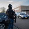 Maskierte und bewaffnete niederländische Polizisten bewachen einen Transport mit einigen der Verdächtigen, die vor dem Hochsicherheitsgebäude des Gerichts in Amsterdam eintreffen.