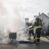 Einsatzkräfte der Feuerwehr löschen ein Feuer, das Demonstranten beim politischen Aschermittwoch der baden-württembergischen Grünen angezündet haben.