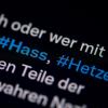 Auf dem Bildschirm eines Smartphones sieht man die Hashtags Hass und Hetze in einem Twitter-Post.