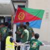 Eritreer stehen vor einem Gebäude, an dess Eingang eine eriteeische Flagge angebraucht ist.