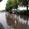 Ein Mitarbeiter leitet die Kundinnen und Kunden in ihren Fahrzeugen vorsichtig durch die tief stehenden Pfützen auf dem Segmüller-Parkplatz.