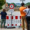 Passanten schauen vom Ufer der Altstadt auf die Hochwasser tragende Donau.