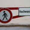 Ein Hochwasser-Schild steht an einem überfluteten Feld.