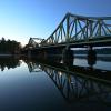 Die Glienicker Brücke spiegelt sich am Morgen im Wasser der Havel.