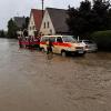 Die Wasserrettung ist in einer überschwemmten Straße in Diedorf im schwäbischen Landkreis Augsburg im Einsatz