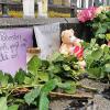 Kerzen und Blumen stehen am Tatort auf dem Marktplatz neben einem Schild "Wer Polizisten angreift, greift uns alle an!".