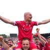 Maximilian Krauß von Cottbus und seine Mitspieler bejubeln nach Schlusspfiff und Platzsturm den Aufstieg mit den Fans.