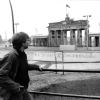 Ein junger Mann steht im April 1984 auf einem Aussichtspodest vor dem Brandenburger Tor und blickt über die Berliner Mauer nach Ostberlin.