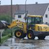 Helfer versuchen eine Straße an der Mindel mit einem Bagger vom Hochwasser zu befreien.