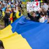 Frauen, Männer und Kinder nehmen mit Fahnen und Transparenten an einer spontanen Kundgebung vor der bayerischen Staatskanzlei angesichts der Lage in der Ukraine teil.