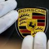 Ein Mitarbeiter befestigt das Markenlogo an einem Porsche im Werk Leipzig.