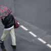 Mit einem Schirm schützt sich eine Passantin vor dem strömenden Regen.